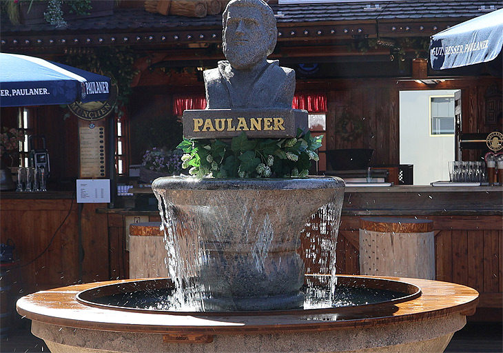 "Isarschänke Weißbiergarten" von Andreas Dräger und Christine Kübler-Dräger mit einem sprudelnden Pailander-Brunnen auf dem Oktoberfest 2025 in der Straße 2 Ost neben Dr. Archibald (©Foto: Martin Schmitz) 